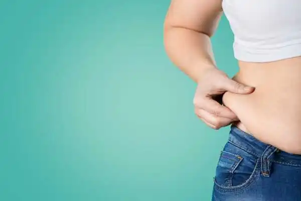 Image of woman pinching her love handles to show weight gain Soho
